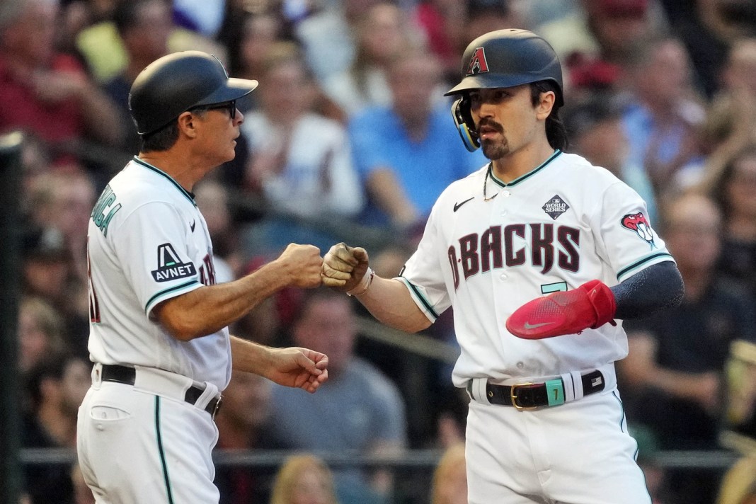 Arizona Diamondbacks left fielder Corbin Carroll fist bumps third base coach Tony Perezchica after taking third base.