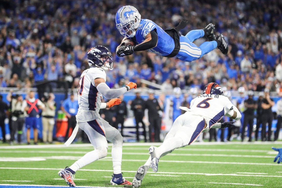 Detroit Lions wide receiver Amon-Ra St. Brown dives for a touchdown over Denver Broncos safety P.J. Locke during the first half at Ford Field in Detroit