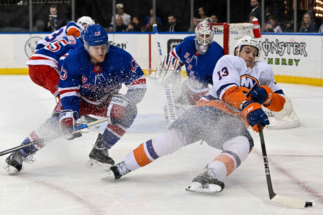 New York Islanders center Mathew Barzal (13) falls while skating with the puck defended by New York Rangers defenseman Adam Fox (23)