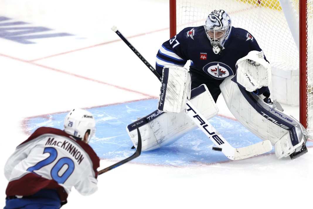 Colorado Avalanche center Nathan MacKinnon takes a shot on Winnipeg Jets goaltender Connor Hellebuyck in the 2024 Stanley Cup Playoffs.