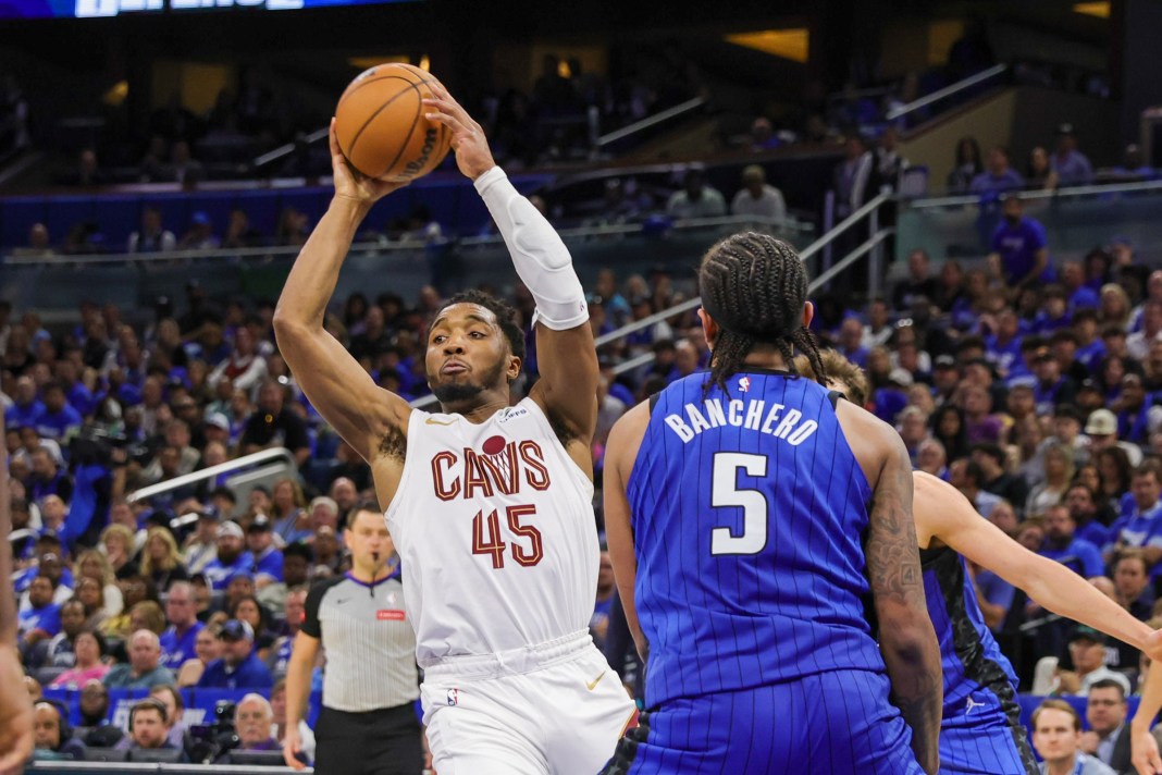 Cleveland Cavaliers guard Donovan Mitchell passes the ball in front of Orlando Magic forward Paolo Banchero in the 2024 NBA playoffs.