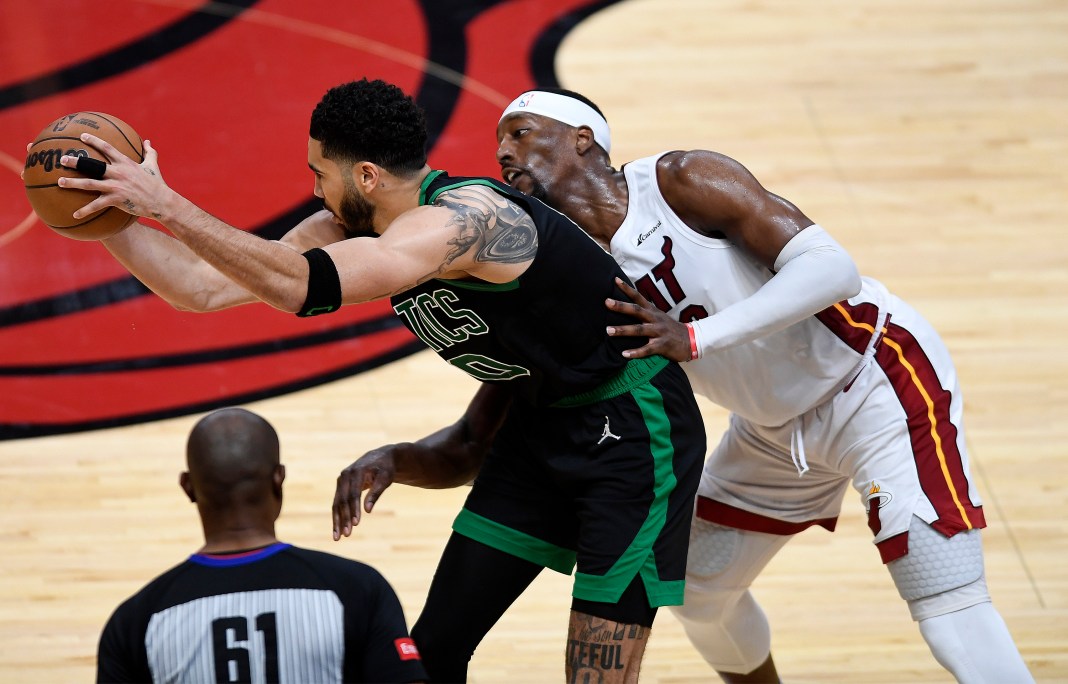 Celtics' Jayson Tatum keeps the ball away from Heat's Bam Adebayo in the 2024 NBA playoffs.