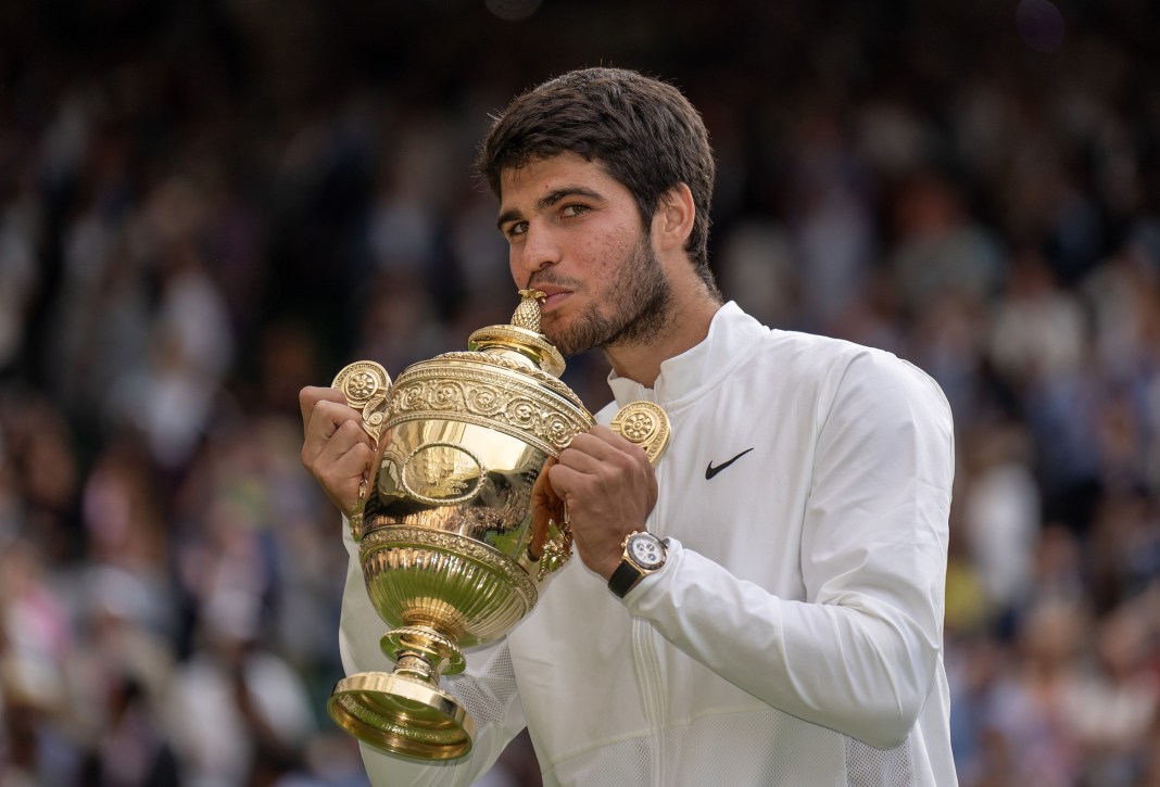 Carlos Alcaraz celebrates his Wimbledon title by kissing the trophy.