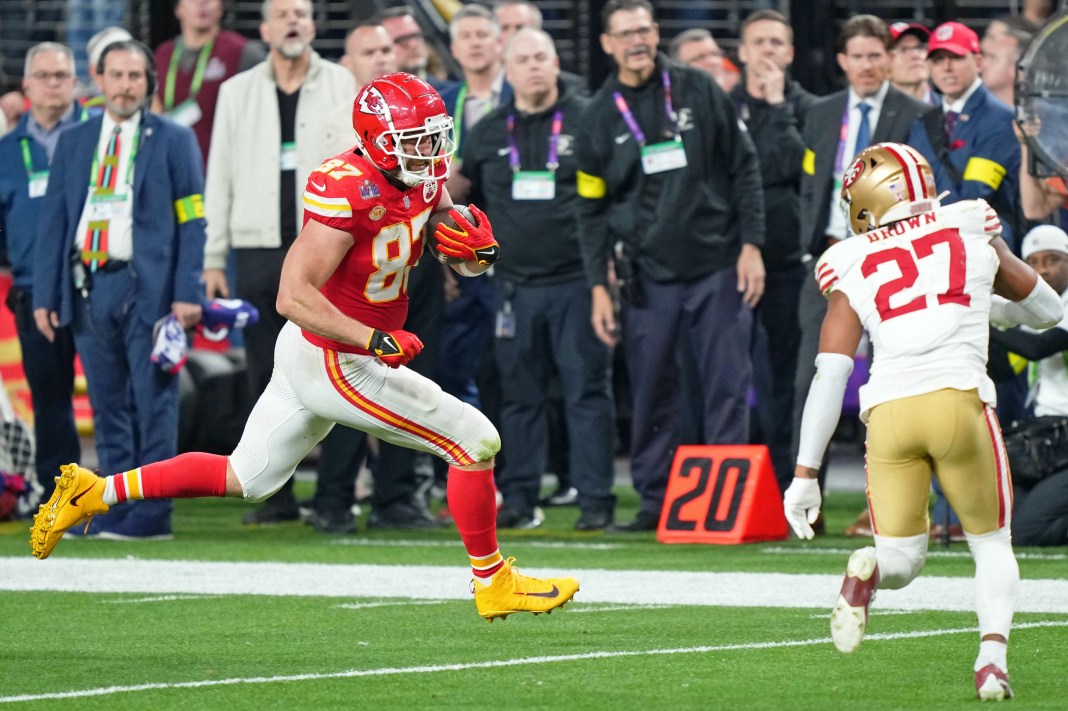 Chiefs' Travis Kelce runs with the ball against 49ers' Ji'Ayir Brown in Super Bowl LVIII.