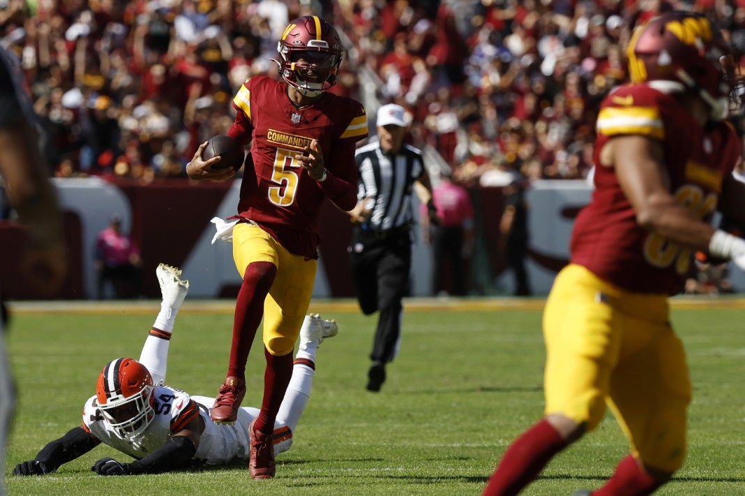 Washington Commanders quarterback Jayden Daniels (5) runs with the ball past Cleveland Browns defensive end Ogbo Okoronkwo (54) during the second quarter at NorthWest Stadium