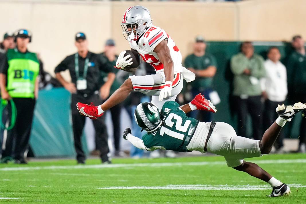 Ohio State Buckeyes running back TreVeyon Henderson hurdles over Michigan State Spartans defensive back Justin Denson Jr.