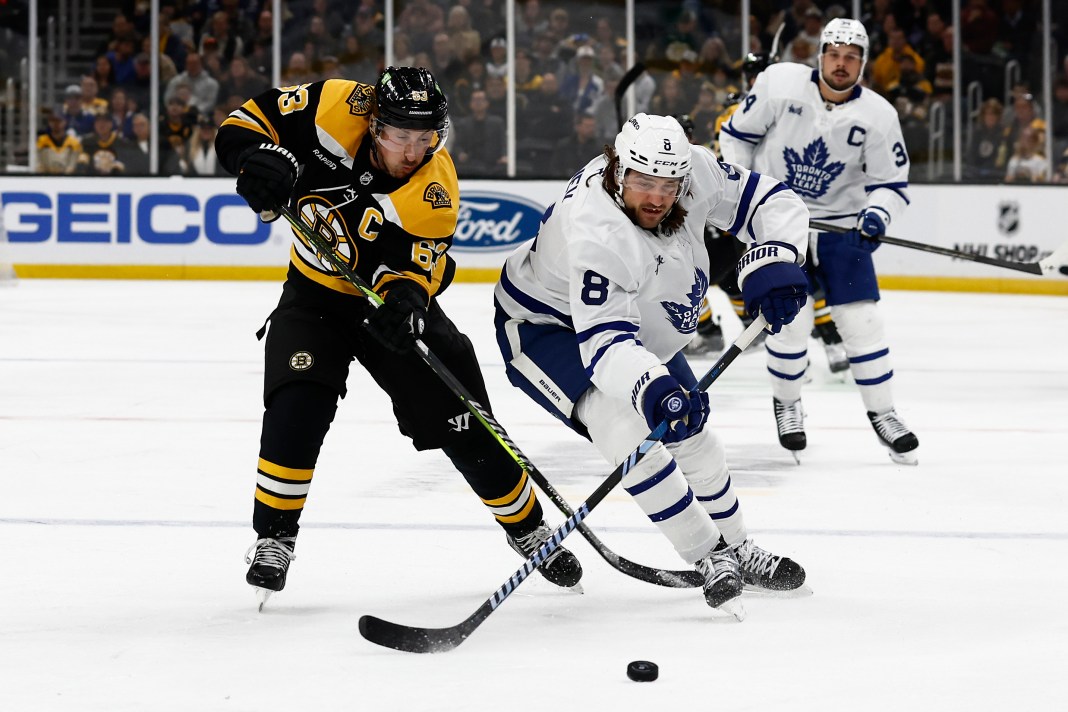 Boston Bruins left wing Brad Marchand and Toronto Maple Leafs defenseman Chris Tanev battle for a loose puck.