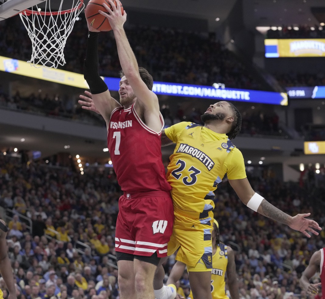 Wisconsin forward Carter Gilmore (7) grabs a rebound over Marquette forward David Joplin (23) during the second half at Fiserv Forum on December 7, 2024.