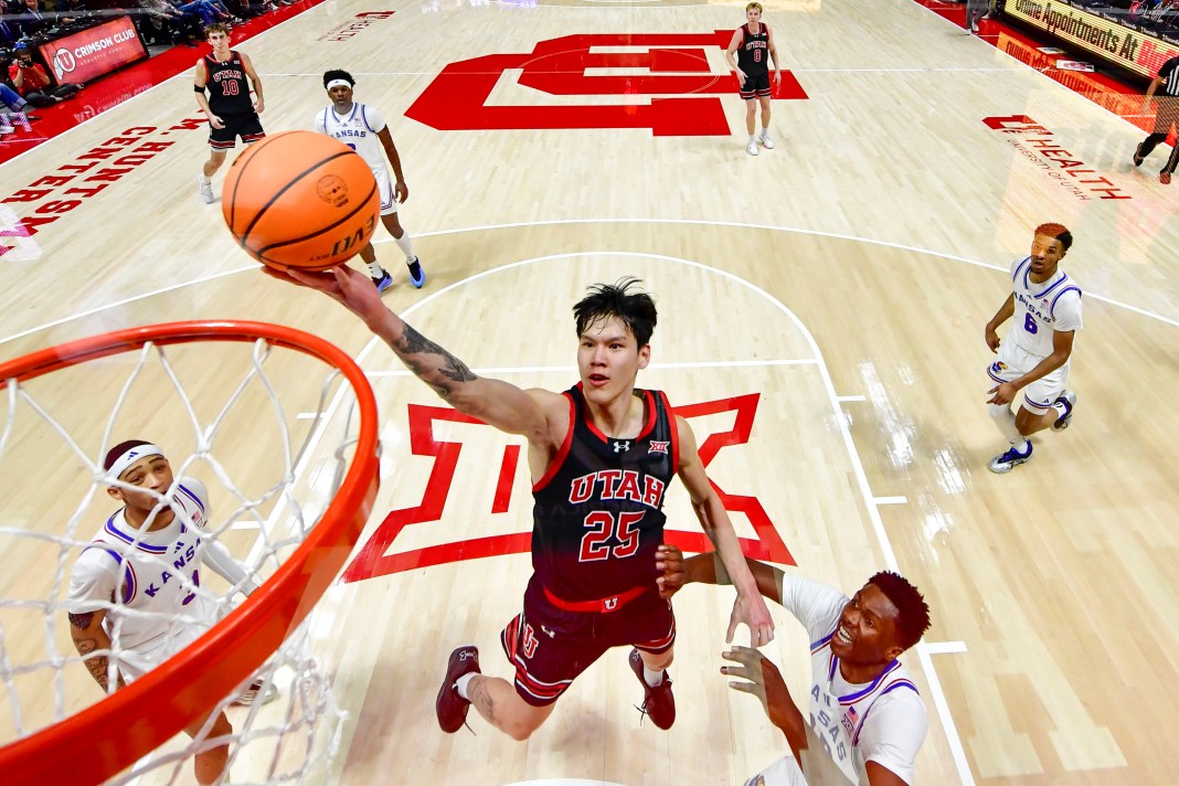 Utah Utes guard Mike Sharavjamts (25) takes a layup over Kansas Jayhawks forward Flory Bidunga (40) during the second half at the Jon M. Huntsman Center on February 15, 2025.